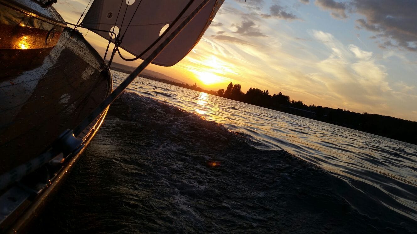 Blick vom Deck über die Bordwand auf den Bodensee bei Sonnenuntergang.
