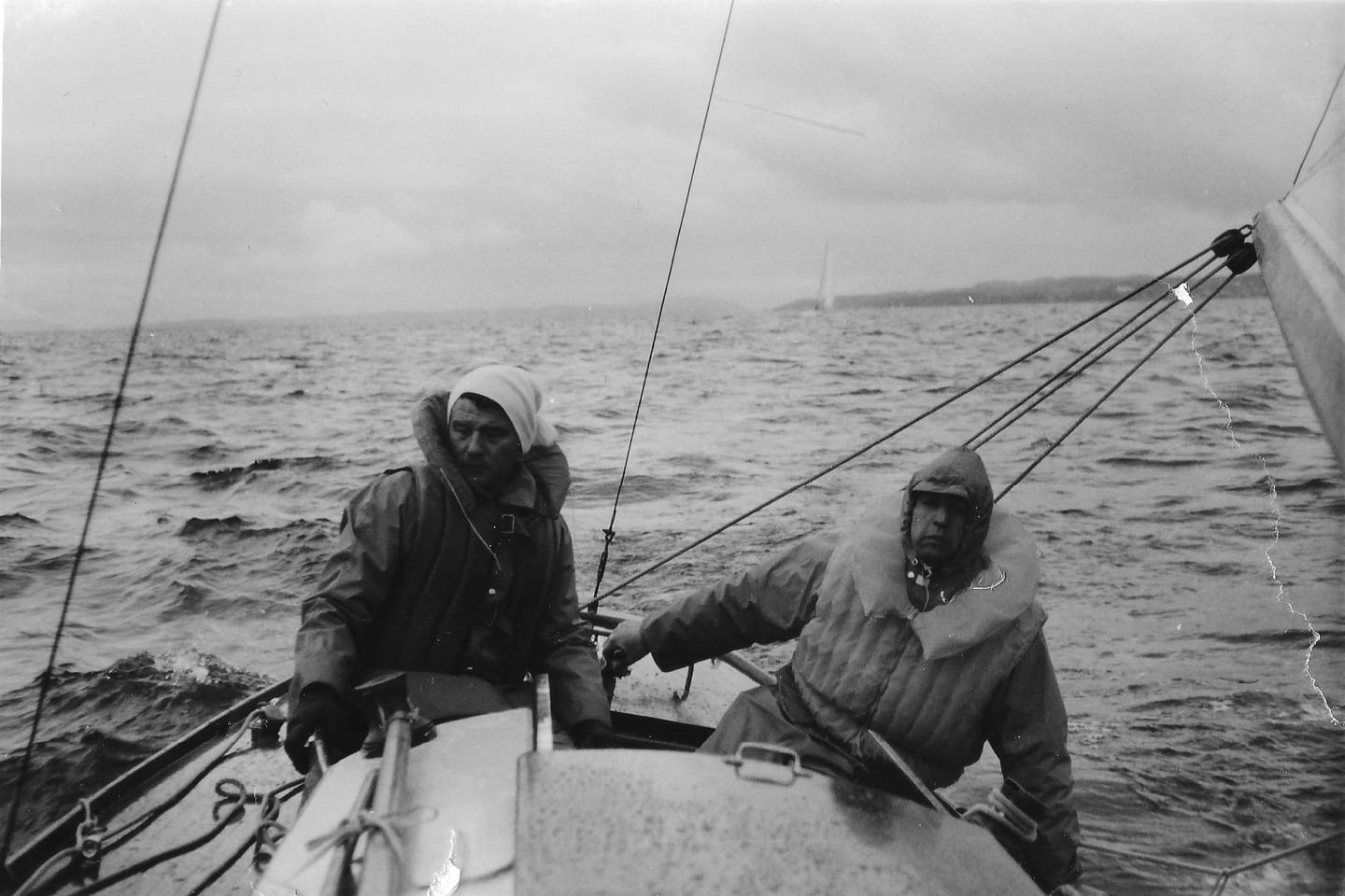 Werner Harder mit Crew in Ölzeug bei Regen und Wind an Bord, Schwarz-Weiß-Aufnahme.
